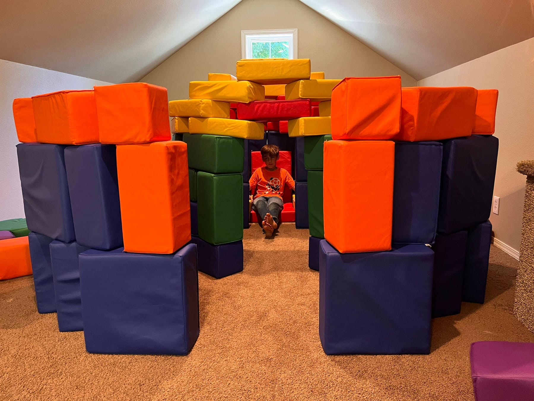 A child sitting inside a soft-block fort