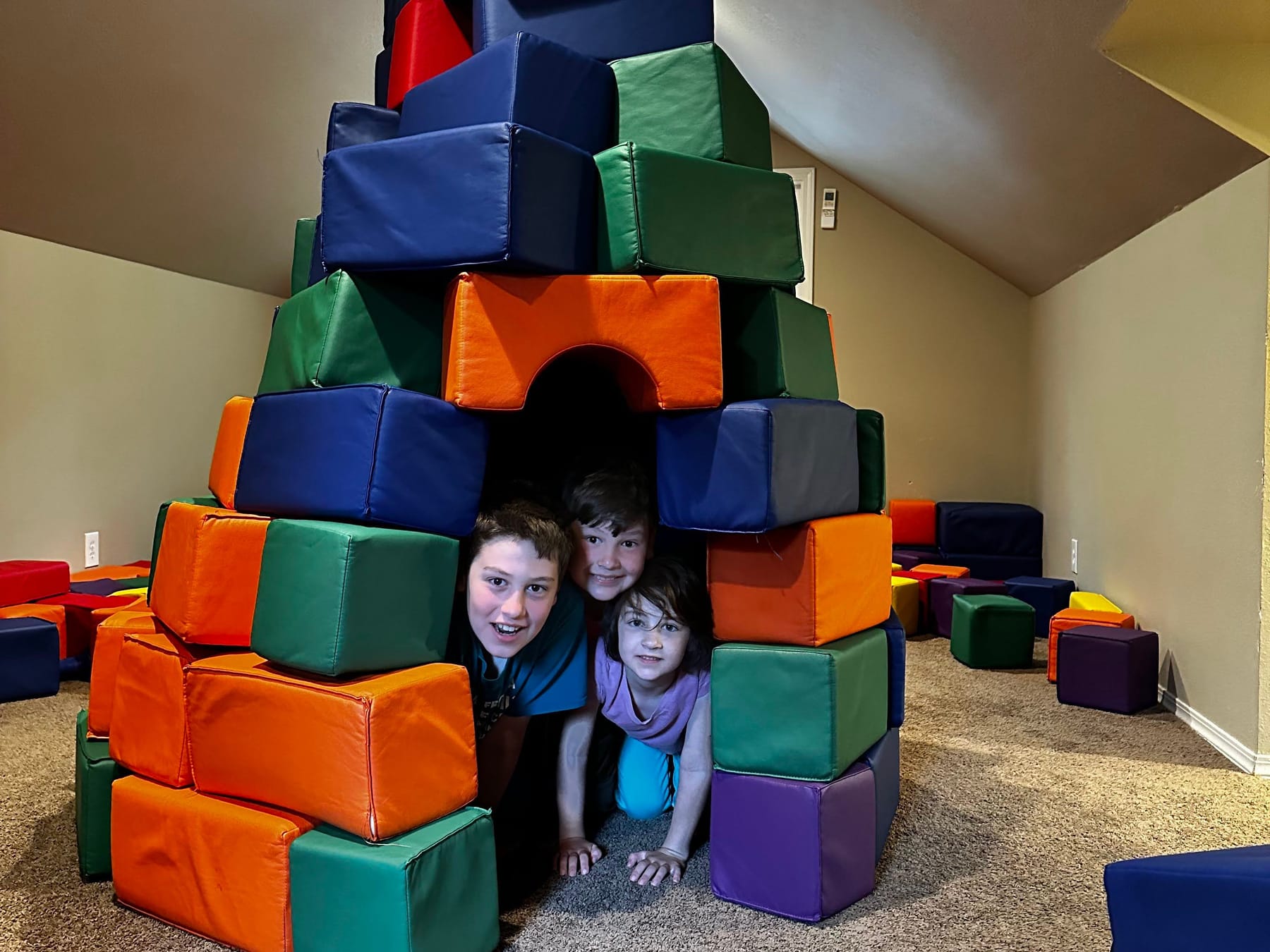 Kids in a doorway they built from soft blocks